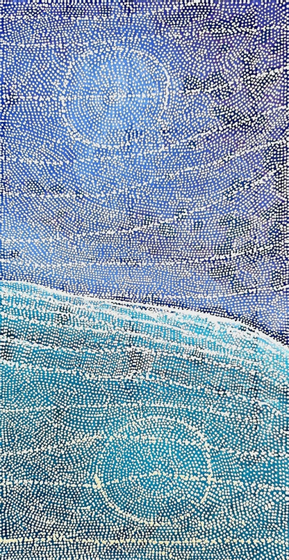 Vertical dot painting by Sarrita King showing an aerial view of cloud filled indigo sky above a turquoise sea, with a pale shoreline between and a large concentric circle suggesting a waterhole near the base.