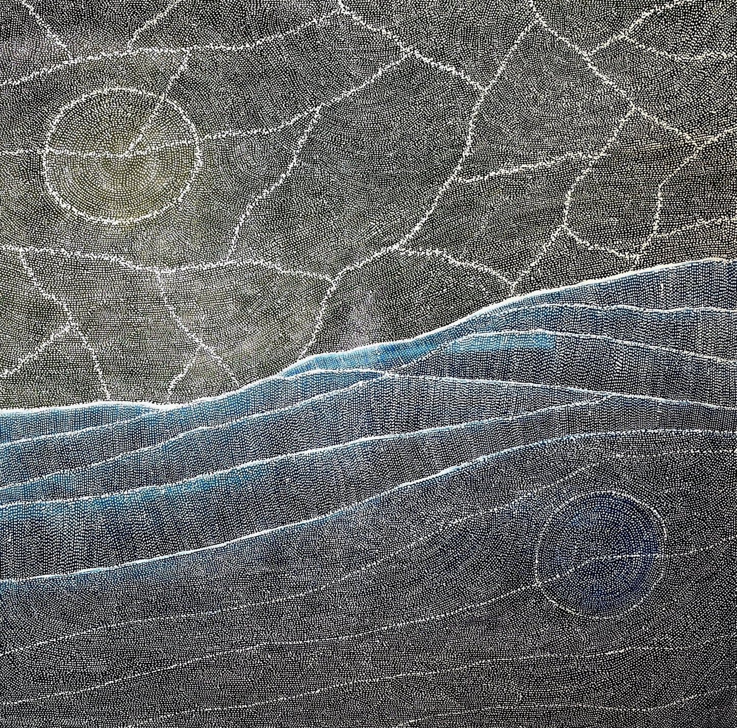 Aerial style dot painting with cracked ochre terrain above and sweeping blue dune lines below, two pale circular forms anchoring opposite corners.