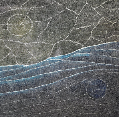 Aerial style dot painting with cracked ochre terrain above and sweeping blue dune lines below, two pale circular forms anchoring opposite corners.